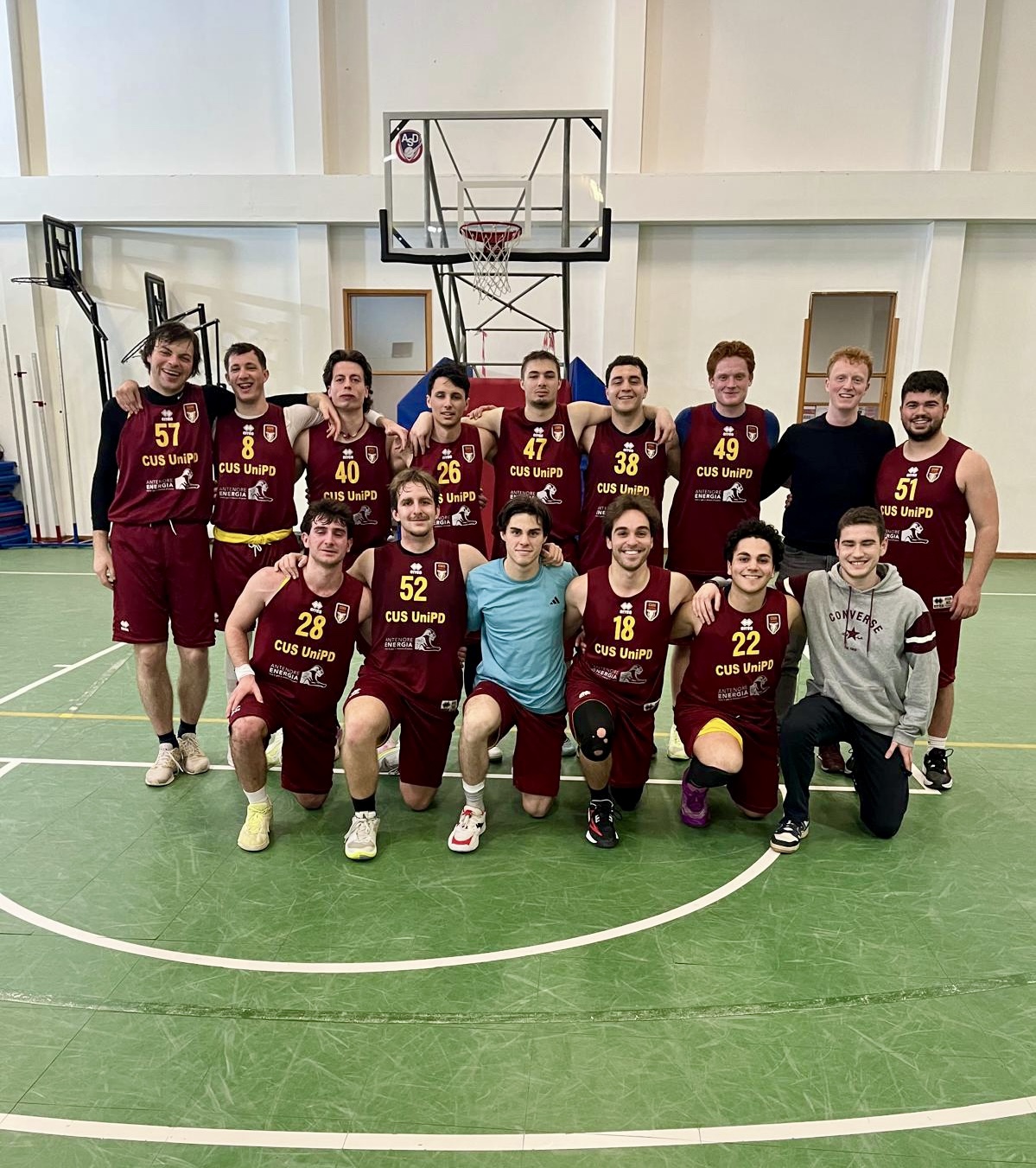 CUS Padova squad posing beneath the basket after a match.